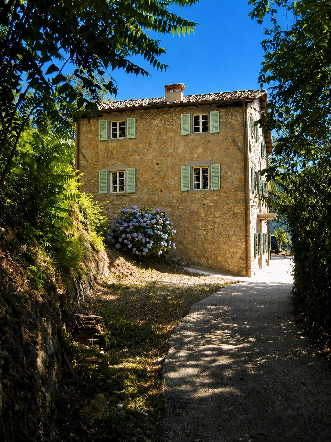 Het traditionele Toscaanse stenen vakantiehuis met sage groene luiken en hortensia bij de voordeur, in Bagni di Lucca